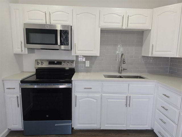 kitchen with decorative backsplash, white cabinets, appliances with stainless steel finishes, and a sink