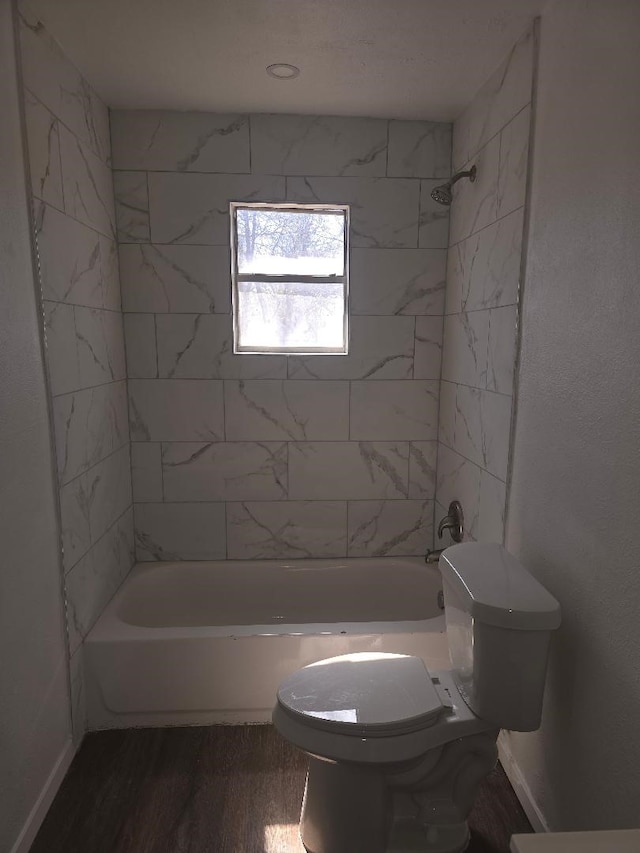 full bath with toilet, wood finished floors, bathing tub / shower combination, and baseboards