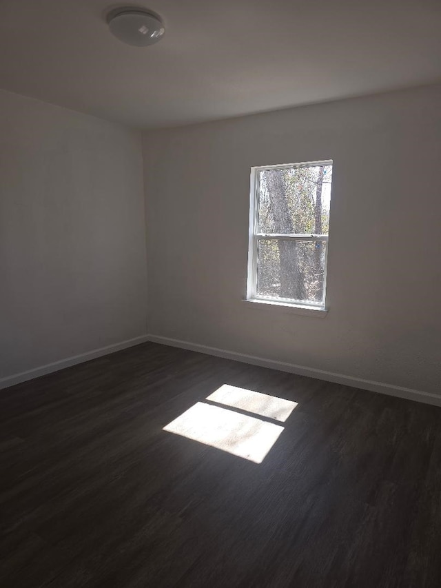 empty room featuring dark wood-style floors and baseboards