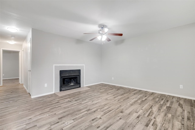 unfurnished living room with a fireplace with flush hearth, light wood-style flooring, baseboards, and a ceiling fan