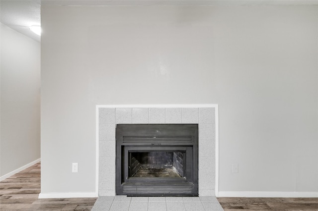 details featuring wood finished floors, a tile fireplace, and baseboards