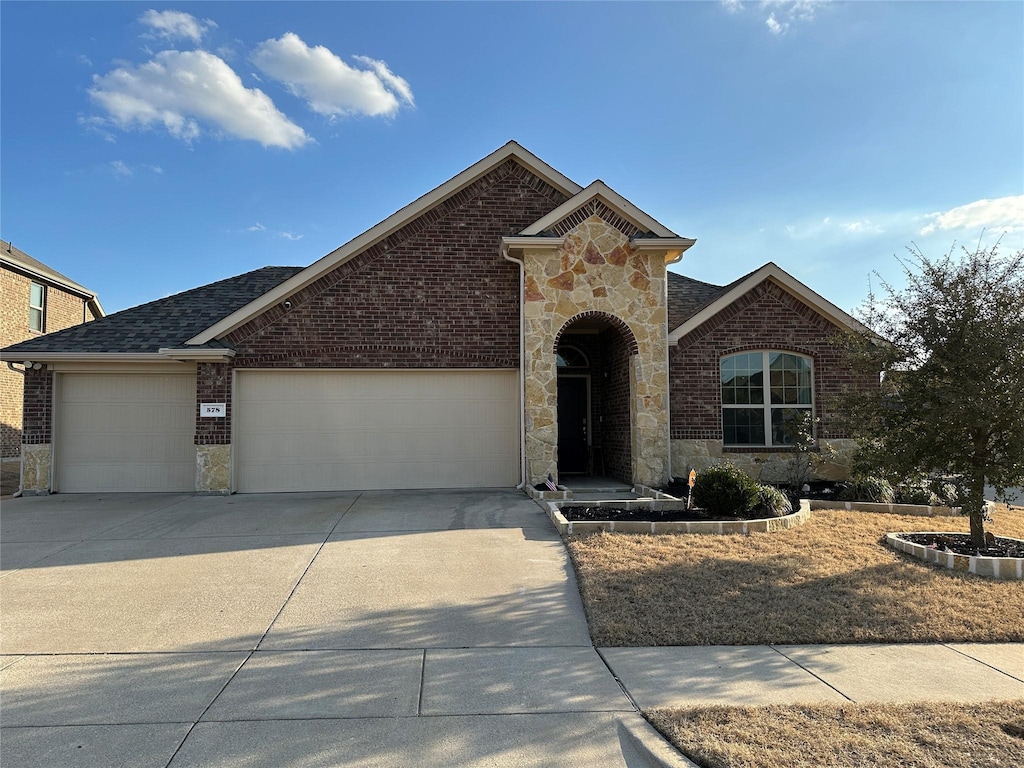 view of front facade with stone siding, brick siding, driveway, and an attached garage