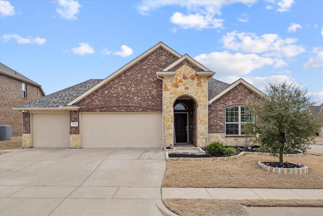 view of front of house with driveway, brick siding, an attached garage, and stone siding