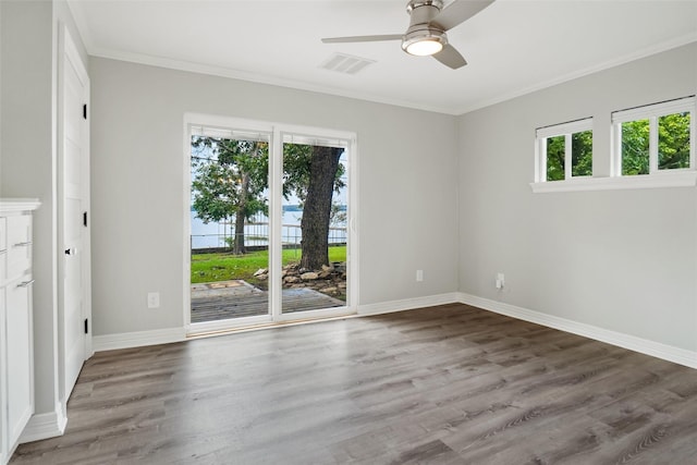 spare room with visible vents, crown molding, baseboards, and wood finished floors