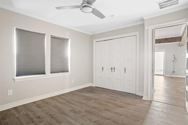 unfurnished bedroom with ornamental molding, visible vents, baseboards, and wood finished floors