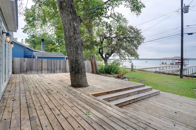 wooden deck with a water view, a lawn, and fence