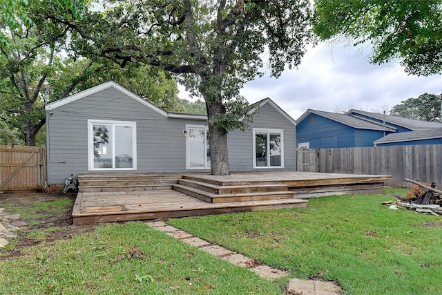 back of house with a deck, a lawn, and fence