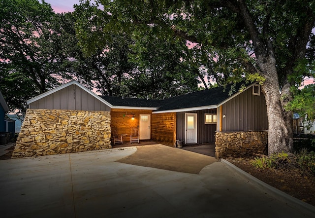 view of front facade with stone siding, board and batten siding, and driveway