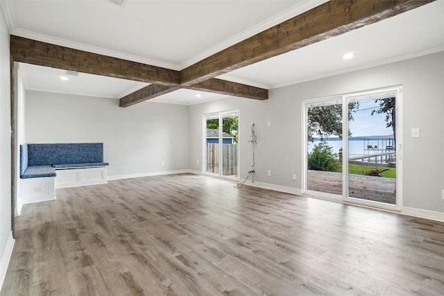 unfurnished living room with crown molding, wood finished floors, and baseboards