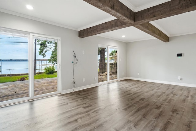 spare room featuring a water view, wood finished floors, baseboards, ornamental molding, and beam ceiling