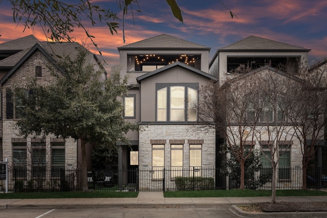 view of front of property with stone siding, a fenced front yard, and stucco siding