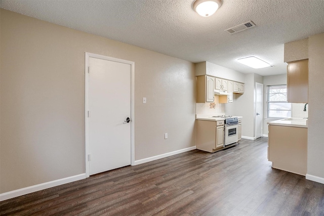 kitchen with light countertops, dark wood finished floors, white range oven, and visible vents