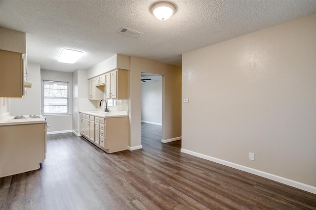 kitchen with dark wood-style floors, light countertops, visible vents, and decorative backsplash