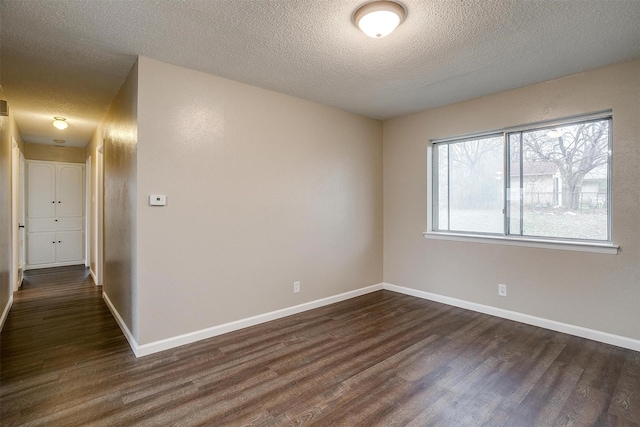 unfurnished room with dark wood-style floors, a textured ceiling, and baseboards