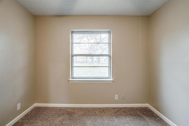 carpeted spare room featuring baseboards, a textured ceiling, and a healthy amount of sunlight