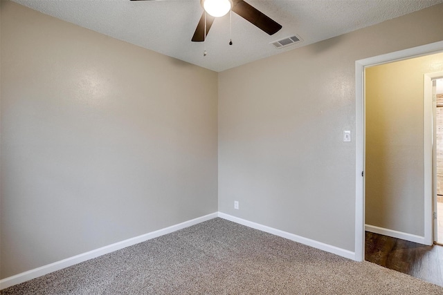 spare room featuring baseboards, visible vents, ceiling fan, dark colored carpet, and a textured ceiling