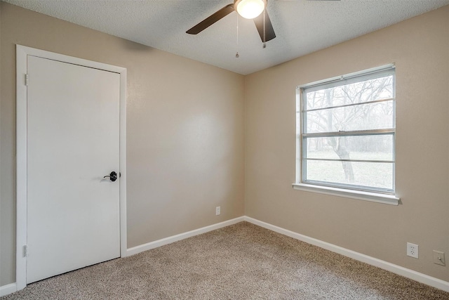 spare room with a textured ceiling, carpet floors, ceiling fan, and baseboards