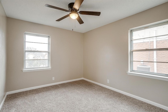 carpeted spare room featuring a ceiling fan, baseboards, and a textured ceiling