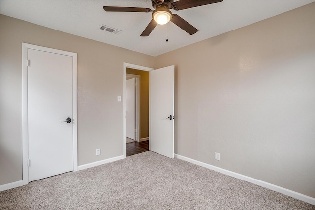 unfurnished bedroom featuring dark colored carpet, a ceiling fan, visible vents, and baseboards