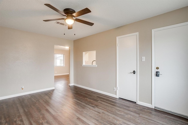 spare room with dark wood-style flooring, visible vents, ceiling fan, a textured ceiling, and baseboards