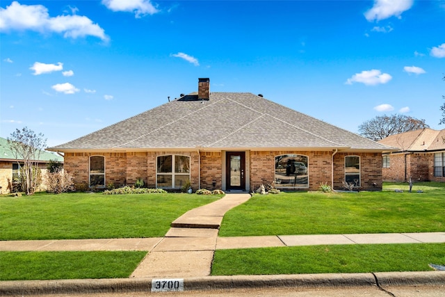 ranch-style home featuring a front lawn, a chimney, a shingled roof, and brick siding