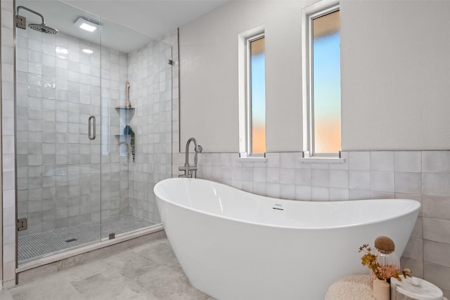 full bath with a soaking tub, wainscoting, tile walls, and a stall shower