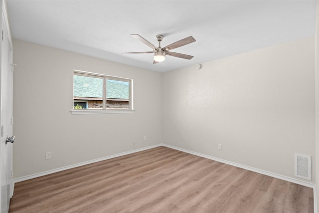 spare room with ceiling fan, light wood finished floors, visible vents, and baseboards