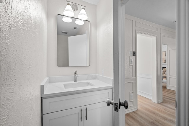 bathroom featuring a textured wall, vanity, and wood finished floors