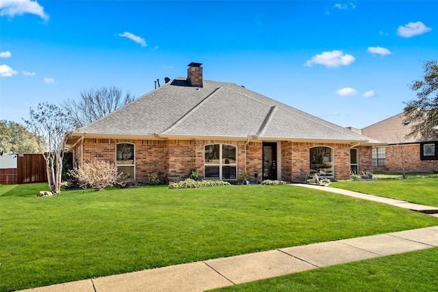 ranch-style house featuring a shingled roof, a front yard, fence, and brick siding