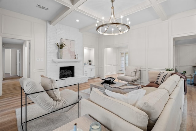 living area with light wood-type flooring, a fireplace, visible vents, and a decorative wall