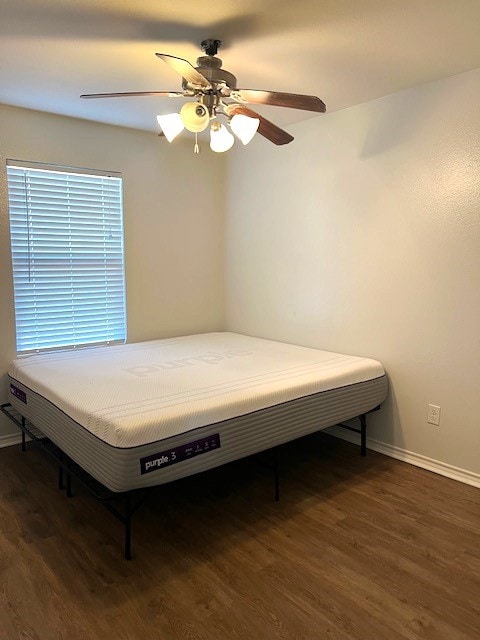 bedroom featuring baseboards, dark wood finished floors, and a ceiling fan