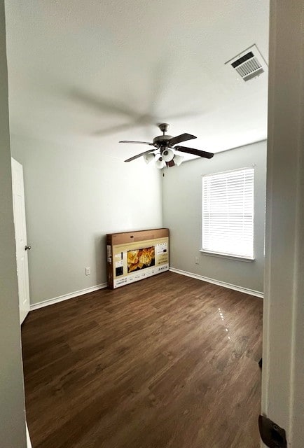 unfurnished living room featuring dark wood-style floors, baseboards, visible vents, and a ceiling fan