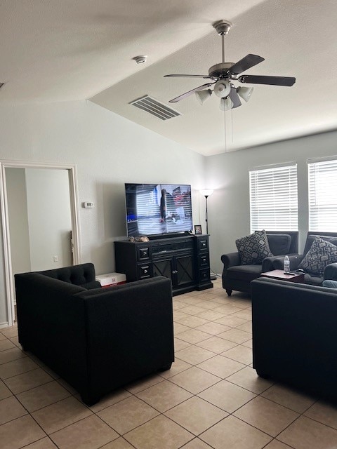 living area with light tile patterned floors, visible vents, ceiling fan, vaulted ceiling, and a textured ceiling