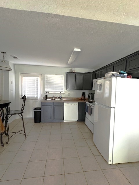 kitchen with white appliances, a textured ceiling, and light tile patterned floors