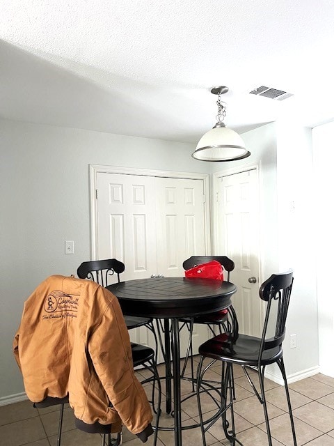 dining area with baseboards, tile patterned flooring, visible vents, and a textured ceiling