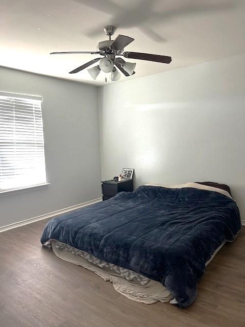 bedroom featuring ceiling fan, baseboards, and wood finished floors