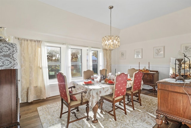 dining room featuring vaulted ceiling, a wainscoted wall, dark wood finished floors, and an inviting chandelier