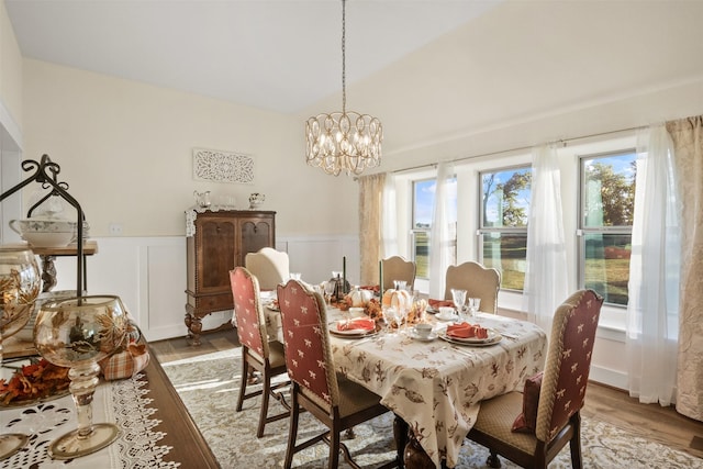 dining area featuring wainscoting, a decorative wall, light wood finished floors, and an inviting chandelier