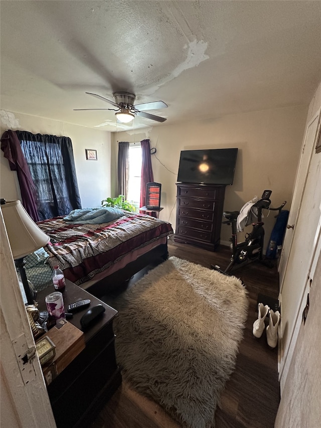 bedroom with dark wood-style floors, ceiling fan, and a textured ceiling