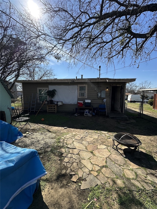 rear view of house with an outdoor fire pit and fence