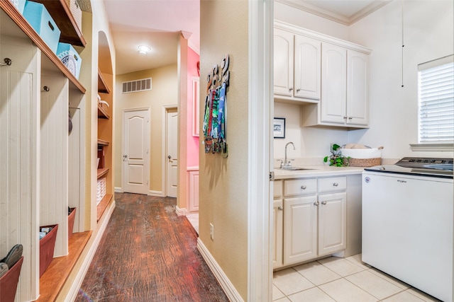 interior space featuring a sink, visible vents, baseboards, ornamental molding, and cabinet space