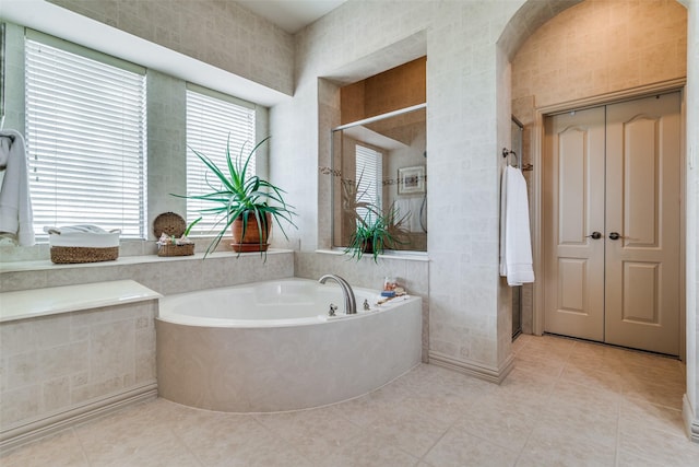 bathroom featuring tile patterned floors, a bath, and tile walls