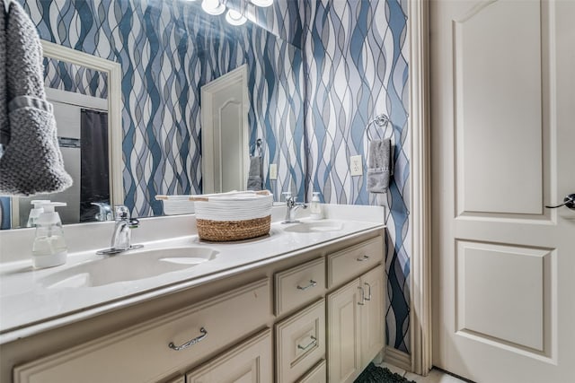 bathroom with double vanity, a sink, and wallpapered walls