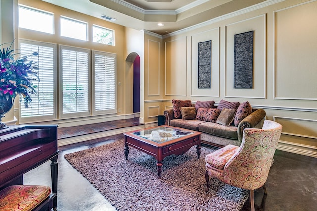 living room featuring arched walkways, crown molding, a wealth of natural light, and a decorative wall