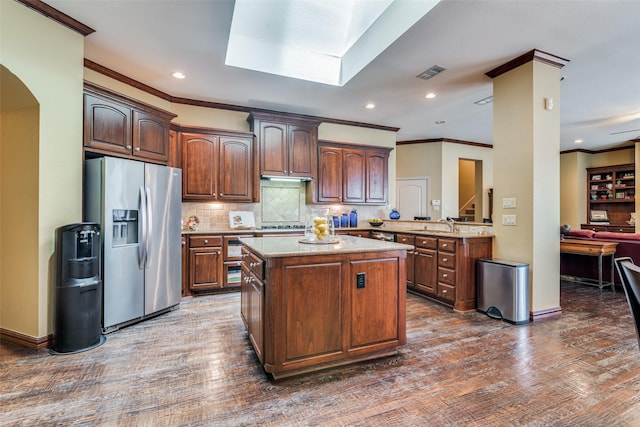 kitchen with a peninsula, visible vents, dark wood finished floors, and stainless steel fridge with ice dispenser