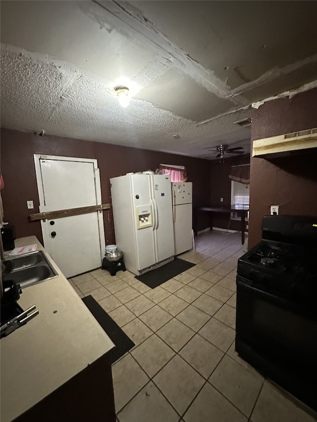 kitchen featuring light tile patterned floors, black range with gas cooktop, white refrigerator with ice dispenser, and freestanding refrigerator