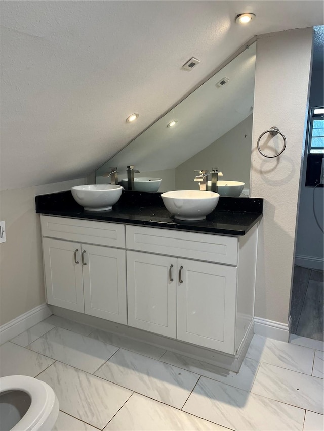 full bath featuring marble finish floor, double vanity, a sink, and visible vents