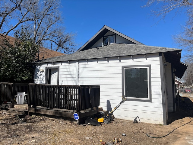 back of property featuring a shingled roof and a wooden deck