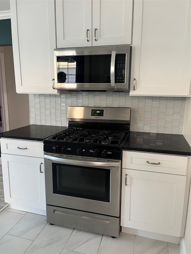 kitchen featuring tasteful backsplash, white cabinets, dark stone counters, marble finish floor, and stainless steel appliances