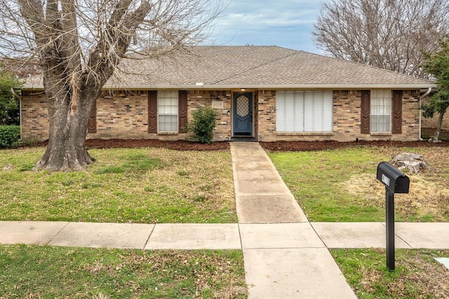 ranch-style house featuring a front lawn, a shingled roof, and brick siding